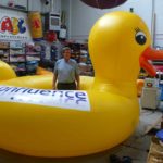 Man standing inside huge yellow duck inflatable