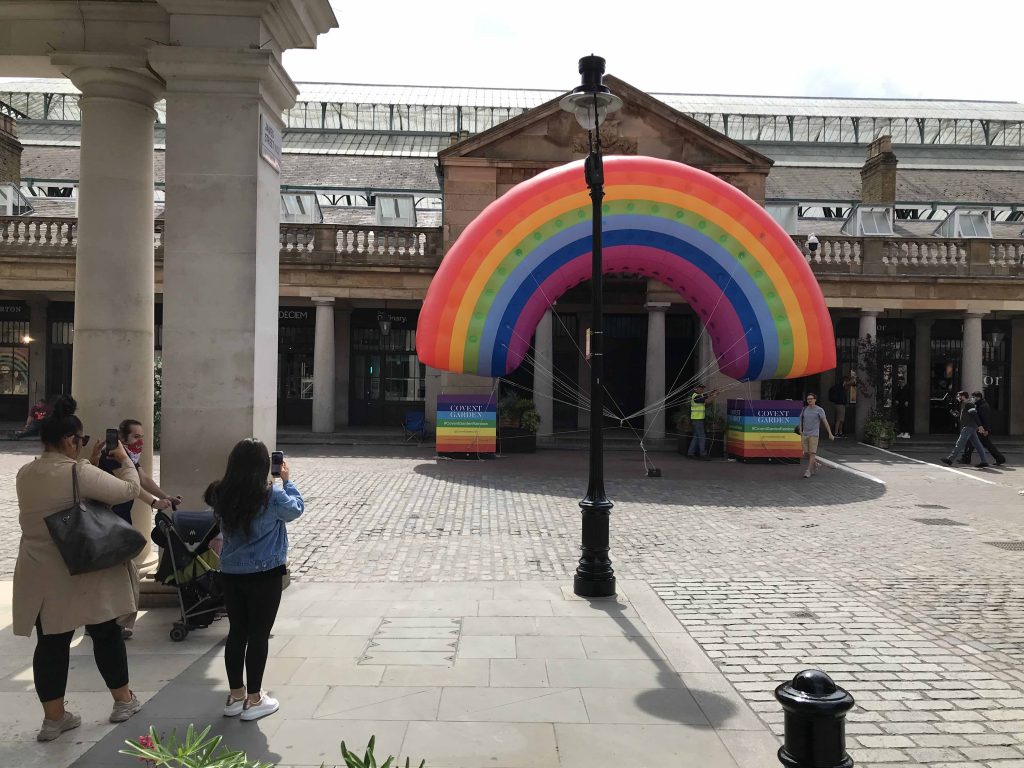 people photographing inflatable rainbow